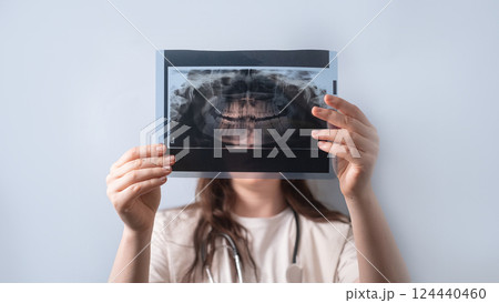Female dentist carefully examines a dental X-ray to identify the cause of the patient's pain. 124440460