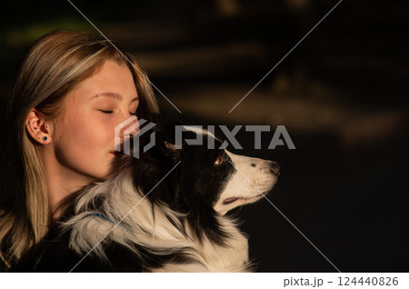Young Caucasian woman hugging her border collie dog while walking in the park.  124440826