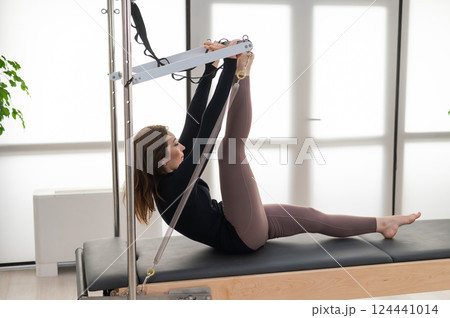 Woman doing Pilates on reformer. Woman doing Pilates on reformer. 124441014