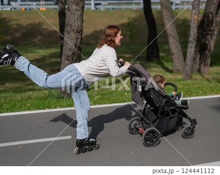 Caucasian woman roller skating with her toddler son in a stroller. Caucasian woman roller skating with her toddler son in a stroller. 124441112