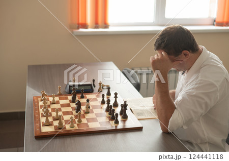 Caucasian man thinking about a chess move. Caucasian man thinking about a chess move. 124441118