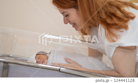 A young mother admires her newborn son in the maternity hospital. A young mother admires her newborn son in the maternity hospital. 124441128