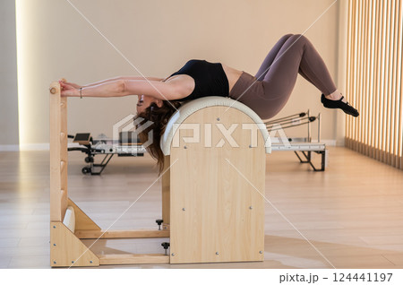 Asian woman exercising on pilates barrel. Asian woman exercising on pilates barrel. 124441197