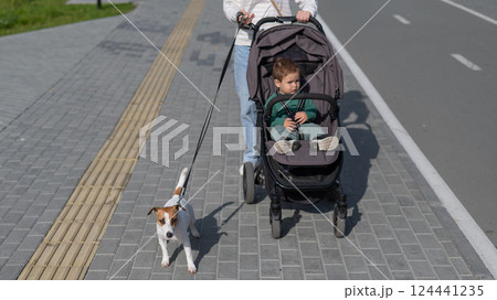 Caucasian woman walks in the park with her one-year-old son and Jack Russell Terrier dog.  124441235