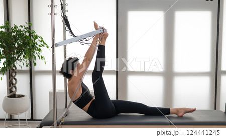 Asian woman doing pilates on reformer. Asian woman doing pilates on reformer. 124441245