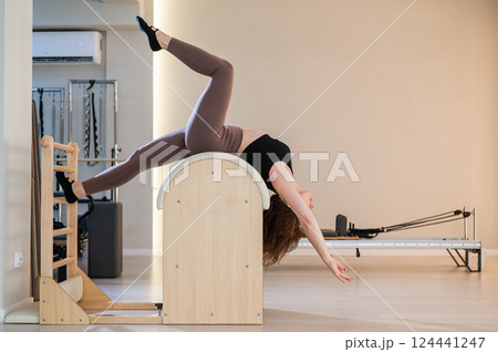 Asian woman exercising on pilates barrel.  124441247