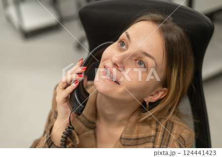 Business woman with braces on her teeth talking on the phone.  124441423