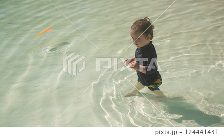 A one-year-old Caucasian boy swims in a pool with a sandy bottom. A one-year-old Caucasian boy swims in a pool with a sandy bottom. 124441431