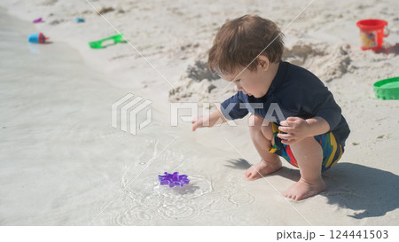 One year old Caucasian boy plays in the sand on the seashore.  124441503