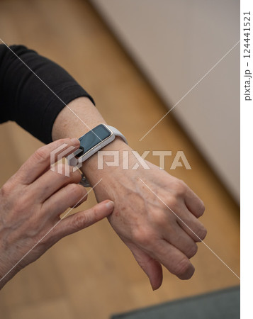 Elderly Caucasian woman looking at smart watch. Close-up of hands. Elderly Caucasian woman looking at smart watch. Close-up of hands. 124441521