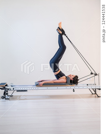 Asian woman doing pilates on reformer.  124441538