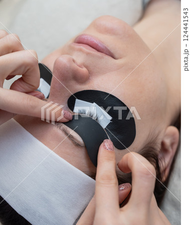 The master applies protective patches that do not let in ultraviolet rays before LED eyelash extensions. The master applies protective patches that do not let in ultraviolet rays before LED eyelash extensions. 124441543