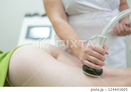 Caucasian woman on hardware anti-cellulite massage. Thigh cavitation procedure. 124441605