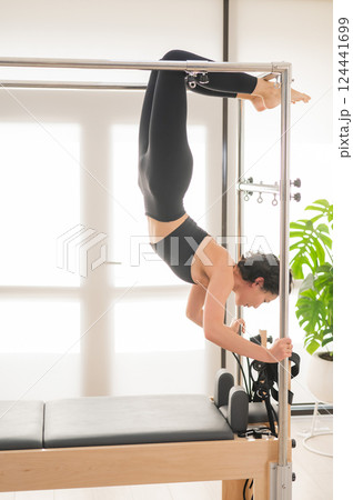 Asian woman doing aerial exercise on reformer machine.  124441699