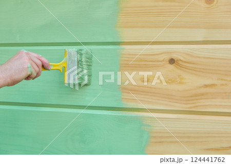 Applying paint wooden surface. Man hand with brush closeup. Painting wood wall. 124441762