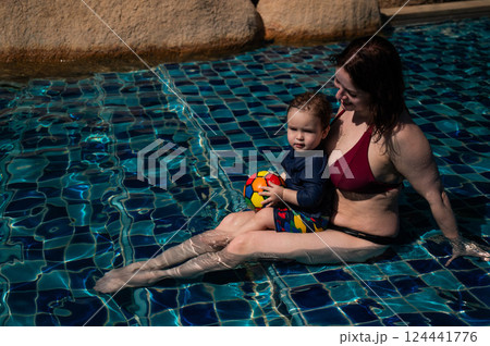 A Caucasian woman and her one-year-old son swim in a pool. 124441776