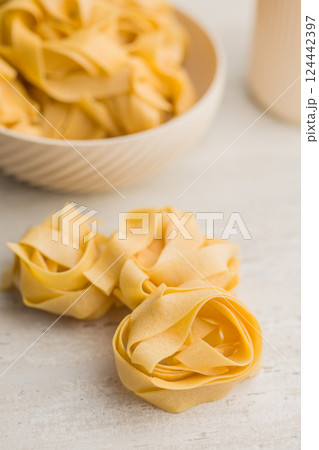 Italian pasta tagliatelle. Uncooked noodle pasta on kitchen table. 124442397
