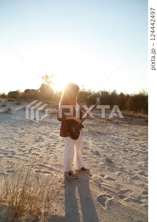 Girl Plays Bass Music Instrument On The Beach At Sunset Near Ocean Girl Plays Bass Music Instrument On The Beach At Sunset Near Ocean 124442497