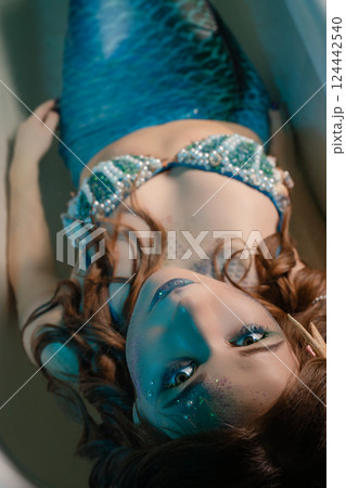 Mermaid cosplay with intricate body art in a serene water setting 124442540