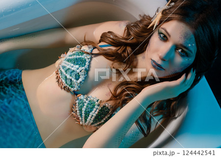 Mermaid posing in body art with intricate details in a bathtub setting 124442541