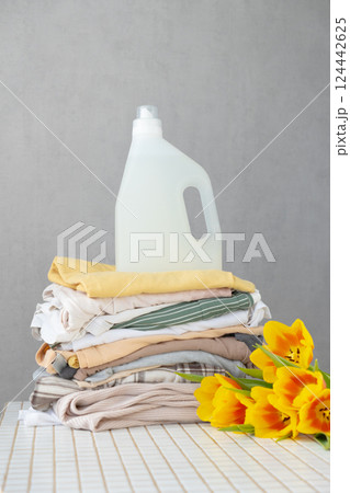 mock up, conditioner, or laundry gel against stack of clean clothes on a table with tulip flowers. mock up, conditioner, or laundry gel against stack of clean clothes on a table with tulip flowers. 124442625