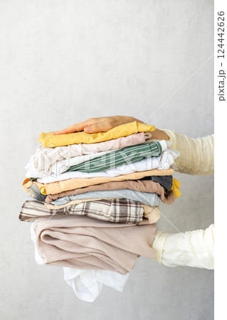 Laundry, woman holds stack of clothes in her hands after dry cleaning. housework, cleaning ironing. Laundry, woman holds stack of clothes in her hands after dry cleaning. housework, cleaning ironing. 124442626