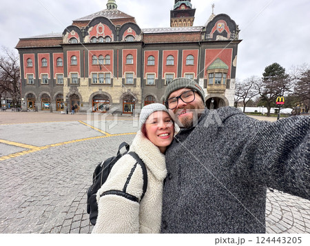 Couple taking selfie in front of historic town hall in Subotica in Serbia on a winter day. Travel, culture, architecture, and joyful relationship concept. East Europe Couple taking selfie in front of historic town hall in Subotica in Serbia on a winter day. Travel, culture, architecture, and joyful relationship concept. East Europe 124443205