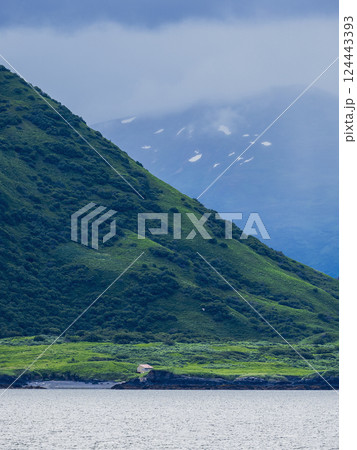 Low clouds covering mountains seen across water 124443393