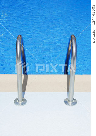 Swimming pool ladder railings and blue water Swimming pool ladder railings and blue water 124443685
