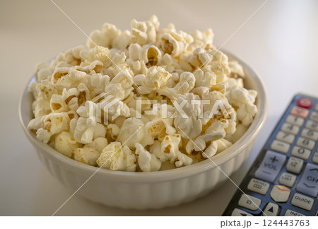Bowl of popcorn and TV remote control Bowl of popcorn and TV remote control 124443763