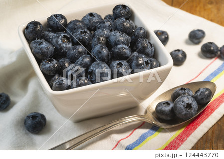 Bowl of  blueberries and spoon on striped dish towel 124443770