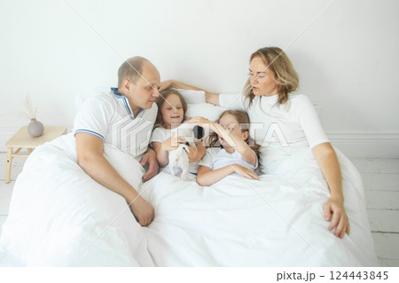 Happy family together. Mother, father, two daughter and dog pet relaxing on the bed at home 124443845