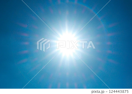 Large sun glaring against clear blue sky Large sun glaring against clear blue sky 124443875
