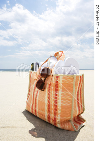Beach bag with sunglasses and flip flops on beach Beach bag with sunglasses and flip flops on beach 124444062