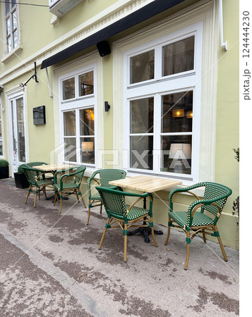 Outdoor cafe seating with empty tables on a quiet city street. Urban lifestyle, social routine, and relaxed street culture. 124444230