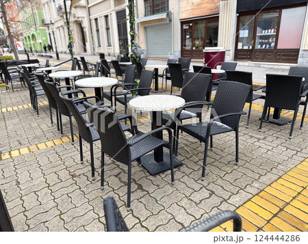 Empty street cafe tables and chairs in a quiet urban setting. City routine, leisure, and public outdoor space in everyday life. Empty street cafe tables and chairs in a quiet urban setting. City routine, leisure, and public outdoor space in everyday life. 124444286
