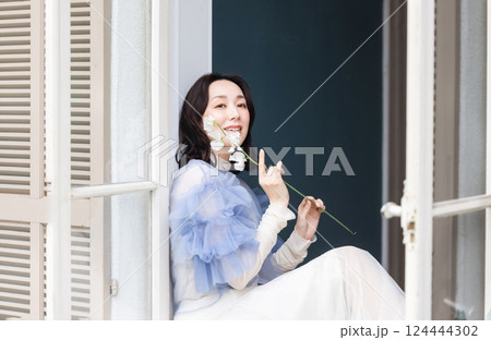 窓辺で花を持つ女性 124444302