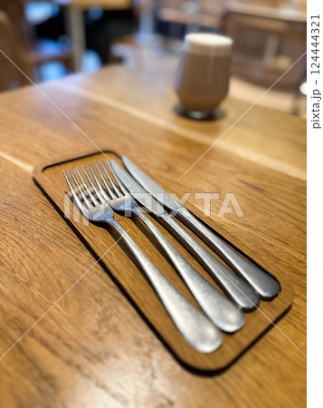 Cutlery on wooden table in cozy restaurant setting. Waiting, simplicity, and daily ritual through minimal composition and objects 124444321