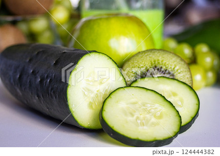 Close-up of cucumber and slices with background of fresh fruits and vegetables 124444382