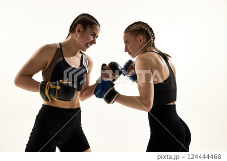 Two female opponents face off with smirks and gloves raised in playful yet focused tension 124444468