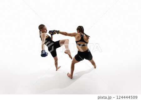 Top view of two female fighters captured mid-strike, training against white background. 124444509
