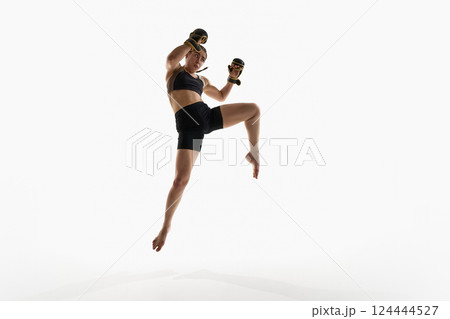 Young woman, fighter jumping with raised fists wearing boxing gloves isolated on white background. 124444527
