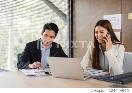 Business Meeting and Collaboration. Two professionals discussing financial reports in a modern office setting. 124444990