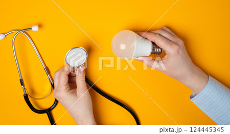 Lamp bulb and stethoscope in female hands. Innovations and ideas in medicine, new concepts, treatments, technologies, and approaches that aim to improve healthcare, solve medical challenges 124445345