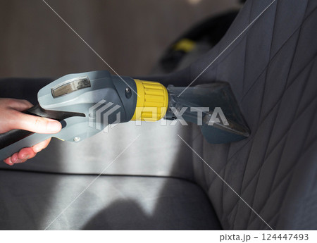 Cleaning the upholstery of a gray chair from dirt with a washing vacuum cleaner. Cleaning services, close-up. Industry 124447493