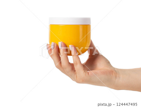 Yellow jar with restorative and nourishing hair mask in hand on white background, isolate, close-up 124447495