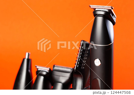 Modern set of hair trimmer with different attachments on a red background, close-up. Copy space for text 124447508