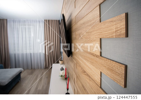 Modern interior in the living room with wooden laminate flooring, wall-hung cabinets, LCD TV and air conditioning. Stylish renovation in the apartment. Copy space for text 124447555