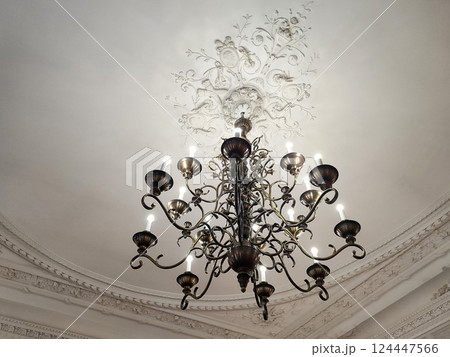 Antique old chandeliers with lamps in the form of candles on the ceiling. Museum lighting, close-up 124447566