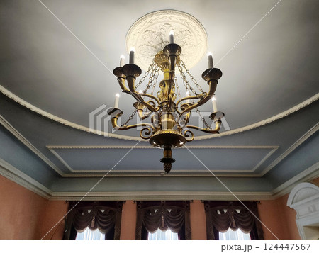 Antique chandeliers in a museum with a ceiling and walls in patterns against the background of a window, close-up 124447567